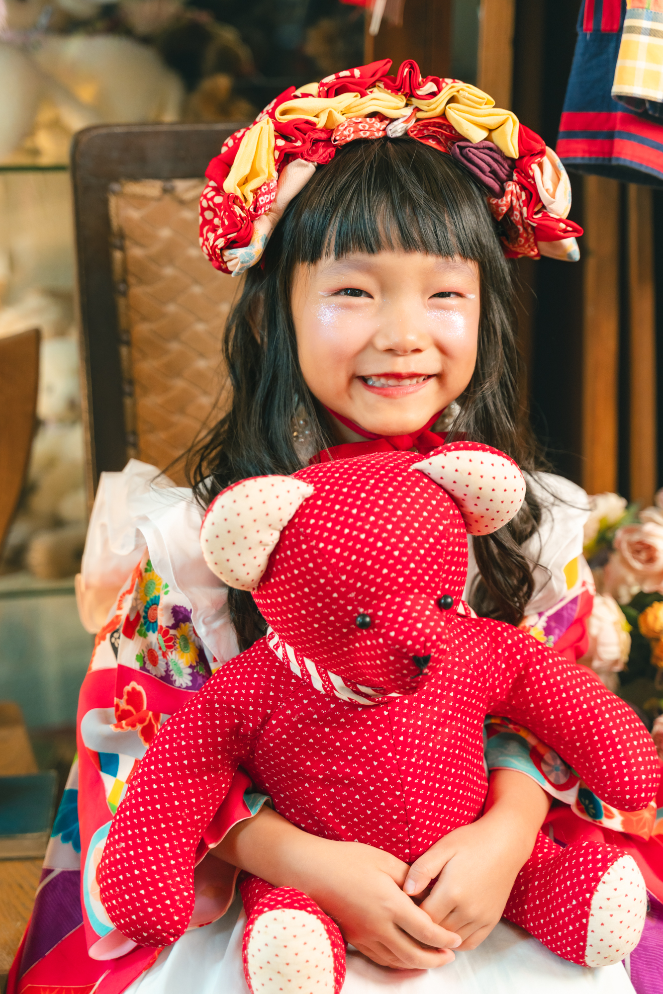 布のヘッドピースを合わせ、赤いくまのぬいぐるみを抱くお子さまの笑顔