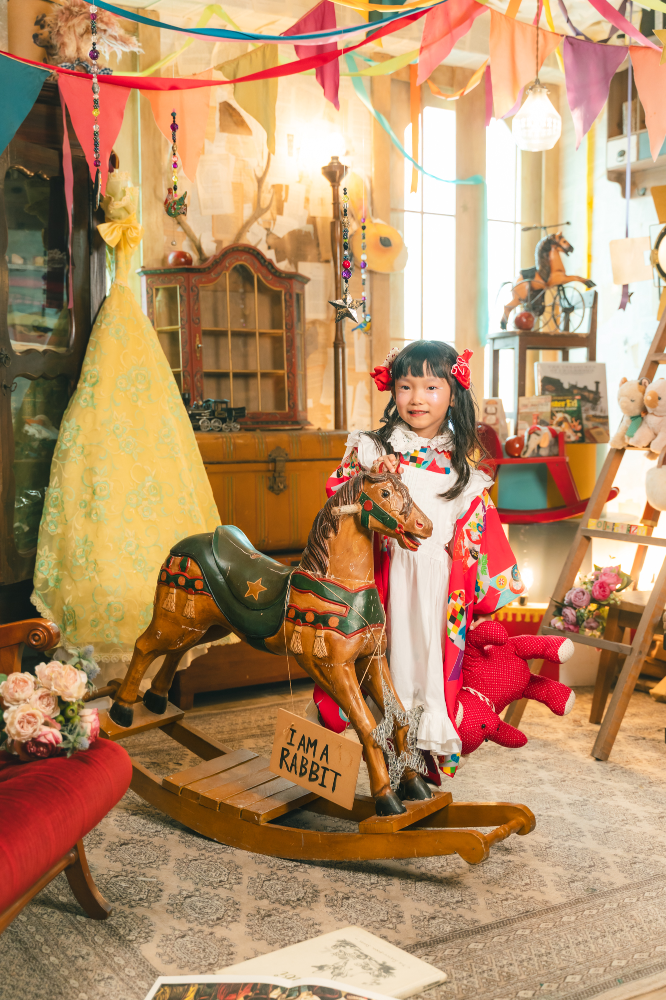 色鮮やかな着物とエプロン姿で木馬のそばに立つお子さま